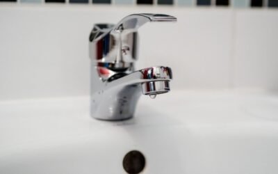 Robinet d'évier en chrome avec goutte d'eau, carrelage blanc, trou d'écoulement